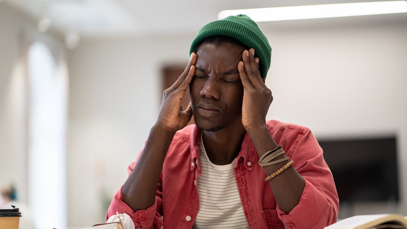 Stressed tired African American student man touching temples have headache after long time preparing for test in college library. Frustrated black hipster male feels nervous afraid of exam failure. ; Shutterstock ID 2272293467