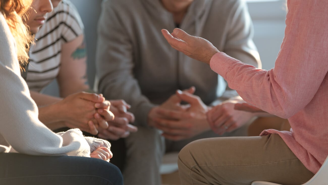 Close-up of a therapist gesticulating while talking to a group of listing teenagers during an educational self-acceptance and motivation meeting.; Shutterstock ID 1150070648