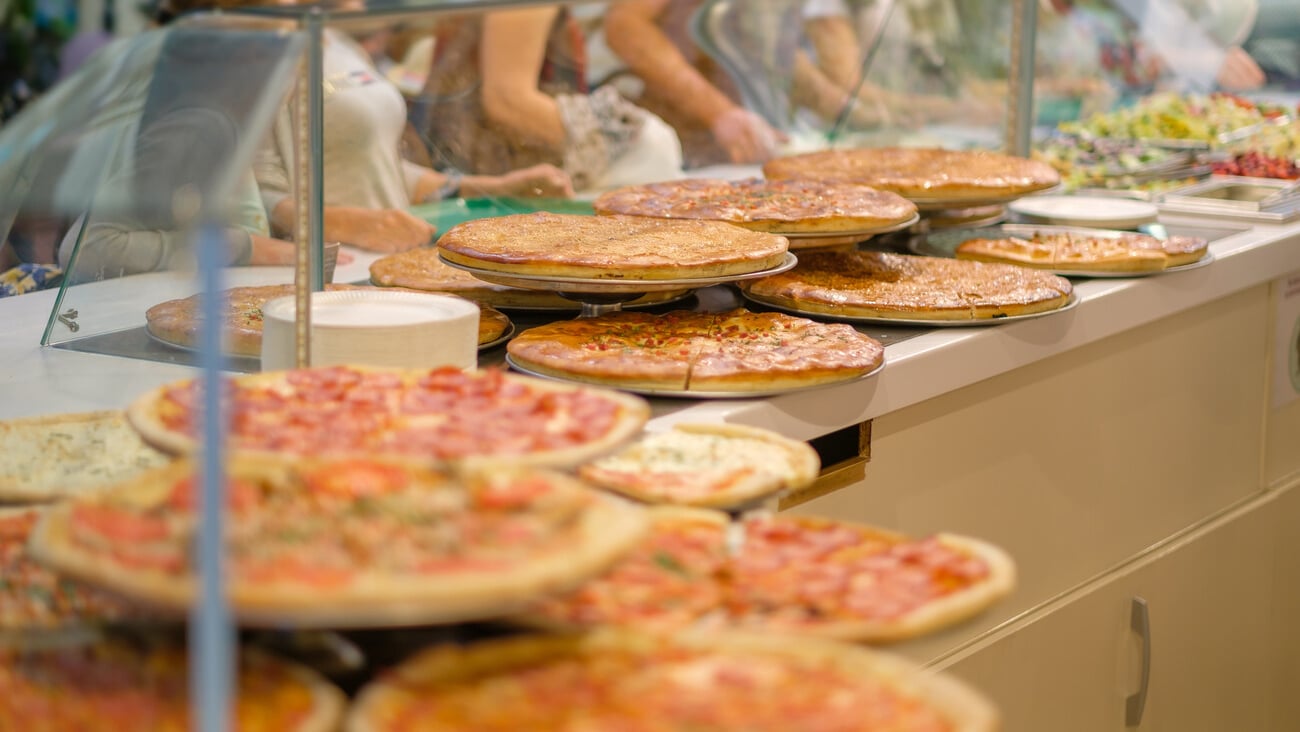 Variety of yummy pizzas under shopping window in pizzeria; Shutterstock ID 676292242