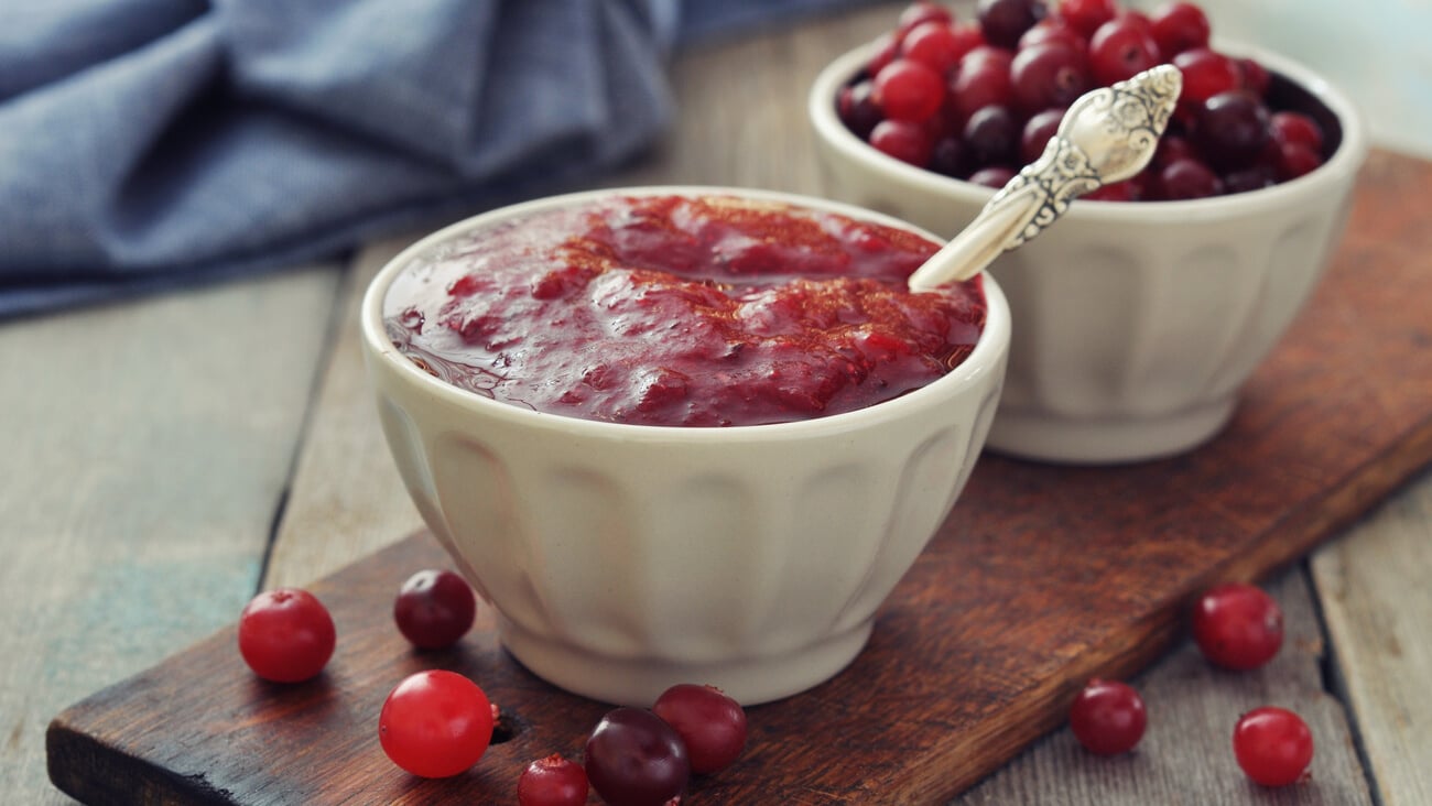 Cranberry sauce in ceramic bowl with fresh berry on wooden background; Shutterstock ID 166304078