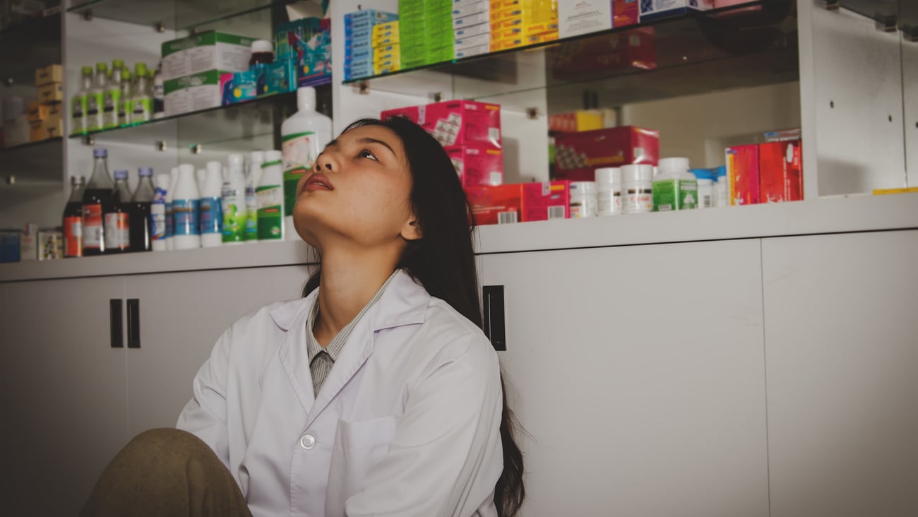 Asian female pharmacist, sitting alone, unhappy in a pharmacy, and sitting thinking about something..; Shutterstock ID 1656330001