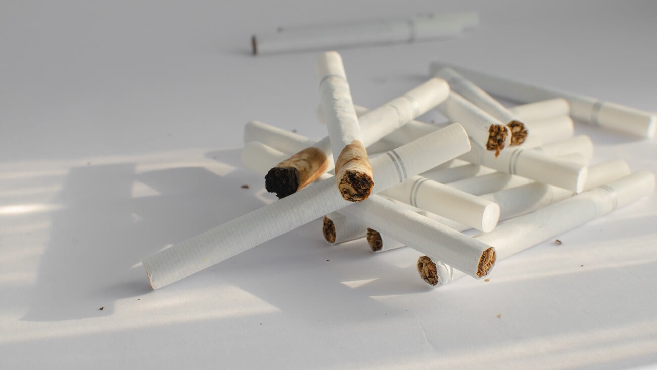 Detail of cigarettes on a white surface, symbolizing the health risks and illnesses associated with smoking.; Shutterstock ID 2353962049