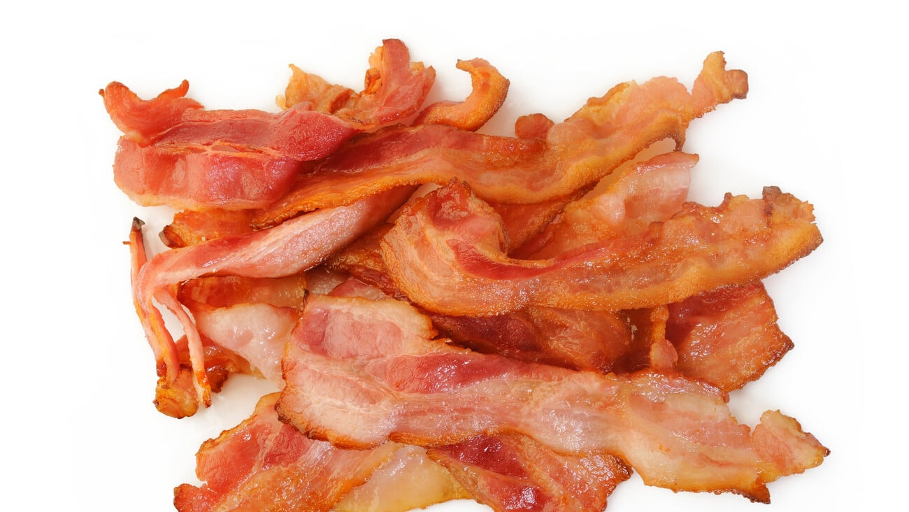 Cooked bacon rashers on white background; Shutterstock ID 1021413904