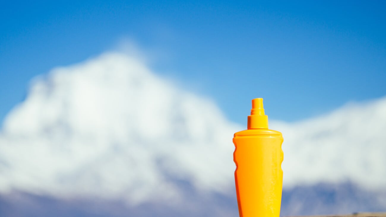 sunscreen in an orange bottle on a mountain background. the concept of preventing skin cancer and the use of sunscreen in the mountains.; Shutterstock ID 1066916534