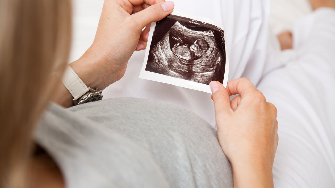 Pregnant woman looking at ultrasound scan of baby, close up of scan; Shutterstock ID 132280742