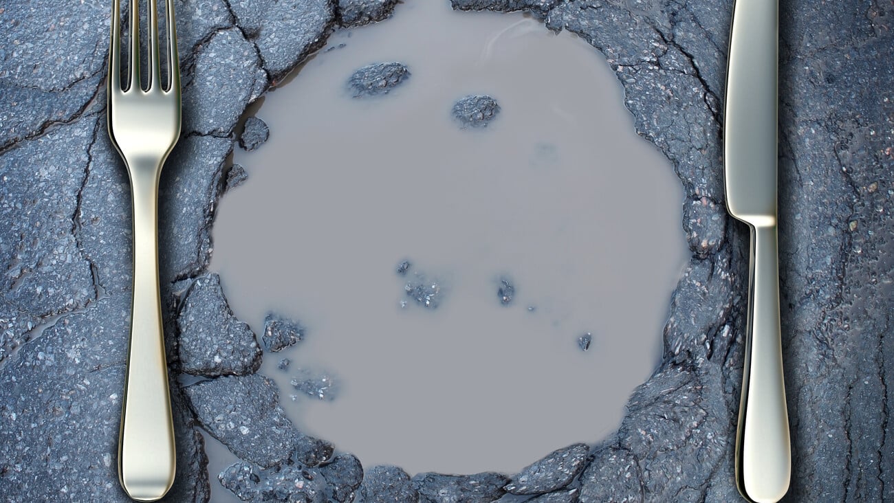 Poverty and hunger concept with a fork and knife on a broken asphalt road shaped as a dinner plate as a social crisis of food shortage hardships and living poor on the streets as a health risk.; Shutterstock ID 145295158