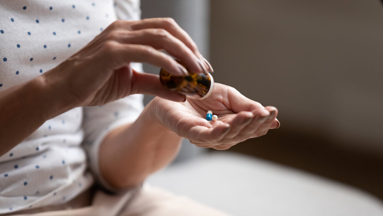 Close up 60s old woman pours out from bottle pills time to take medicaments, cure for memory loss, high blood pressure or cholesterol level remedy pain killer drugs, senile diseases treatments concept; Shutterstock ID 1575688429