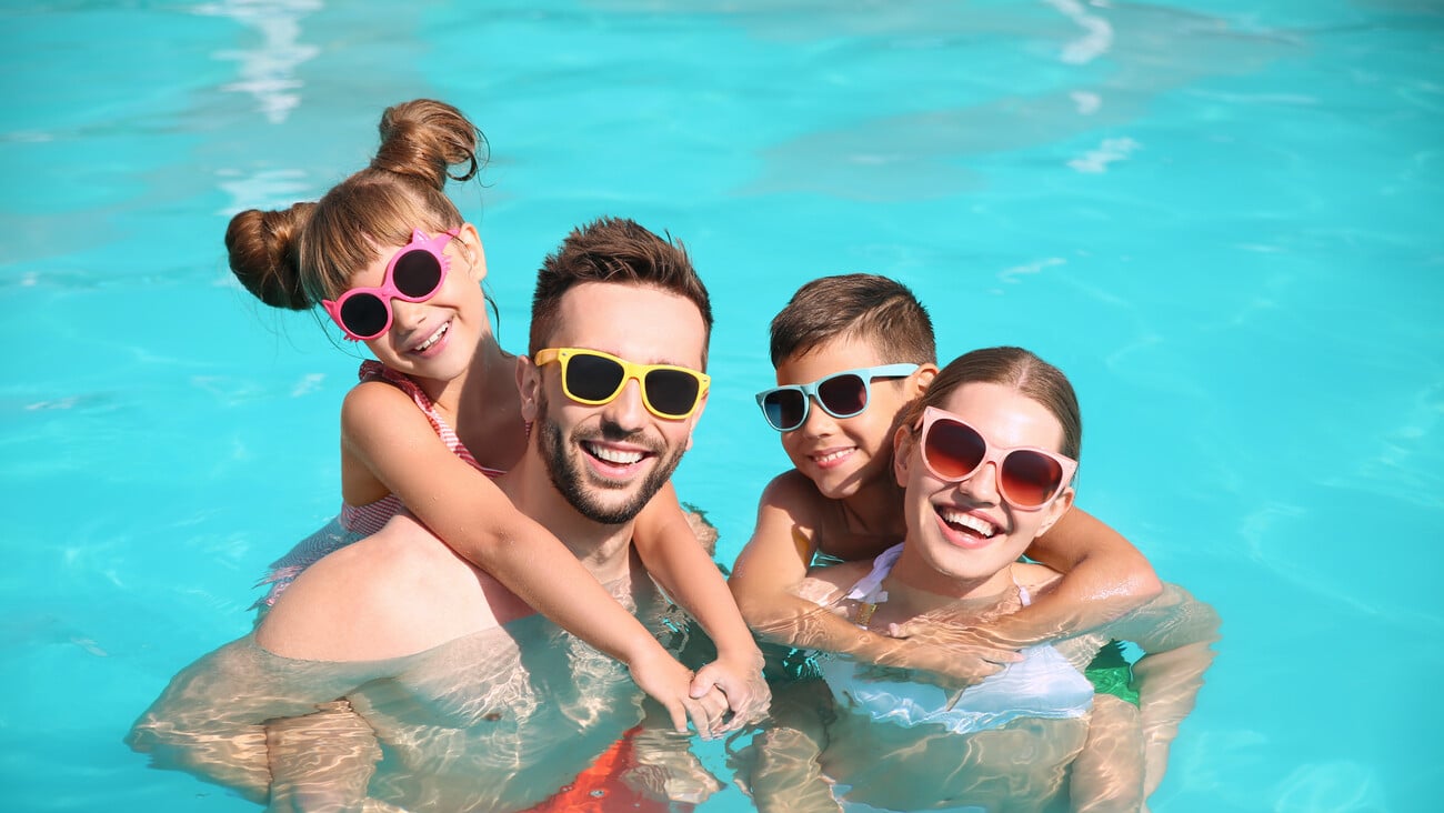 Happy family in swimming pool on sunny day; Shutterstock ID 1796899681