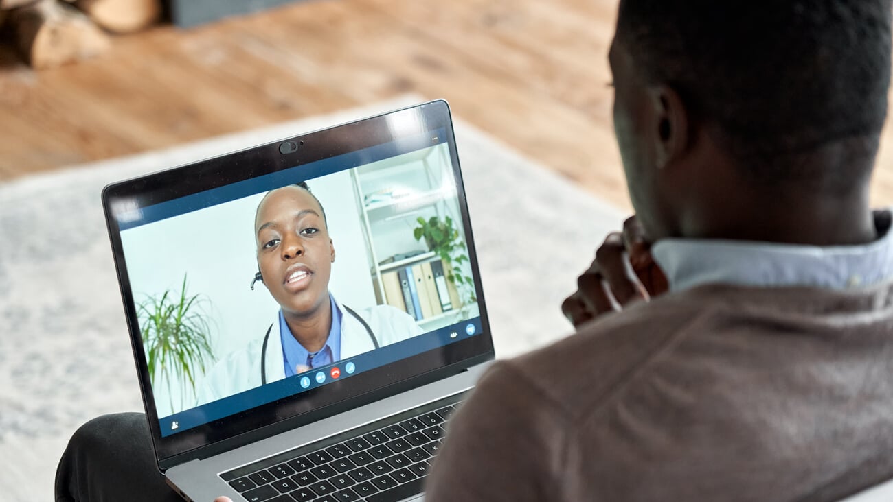 Male black patient on conference video call with female african doctor. Virtual therapist consulting young man during online appointment on laptop at home. Telemedicine chat, telehealth concept.; Shutterstock ID 1854623368