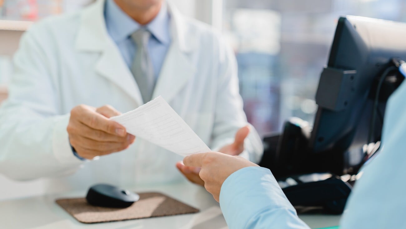 Customer buyer giving chemist pharmacist druggist medical prescription while buying drugs pills for depression, insomnia, antidepressants in pharmacy; Shutterstock ID 2104022123