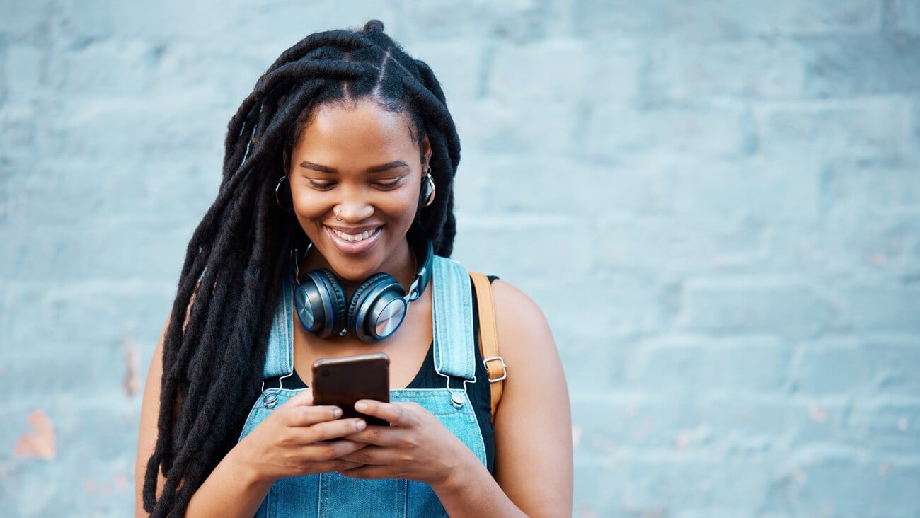 Black woman with 5g smartphone for social media typing, digital chat app or check location on blue wall background space mockup. Teenager gen z girl on cellphone for youth online website networking; Shutterstock ID 2211548835