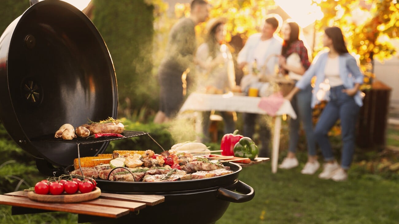 Group of friends having party outdoors. Focus on barbecue grill with food. Space for text; Shutterstock ID 2234937131