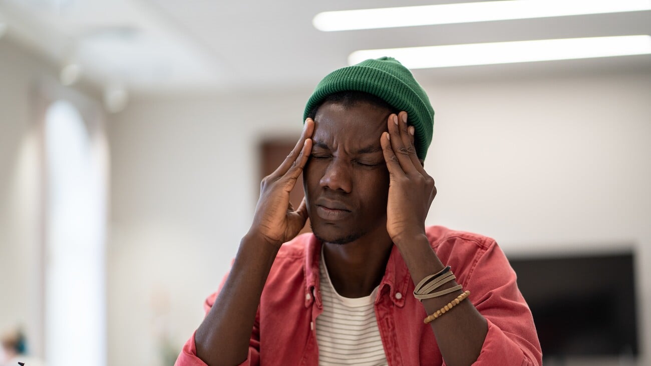 Stressed tired African American student man touching temples have headache after long time preparing for test in college library. Frustrated black hipster male feels nervous afraid of exam failure. ; Shutterstock ID 2272293467