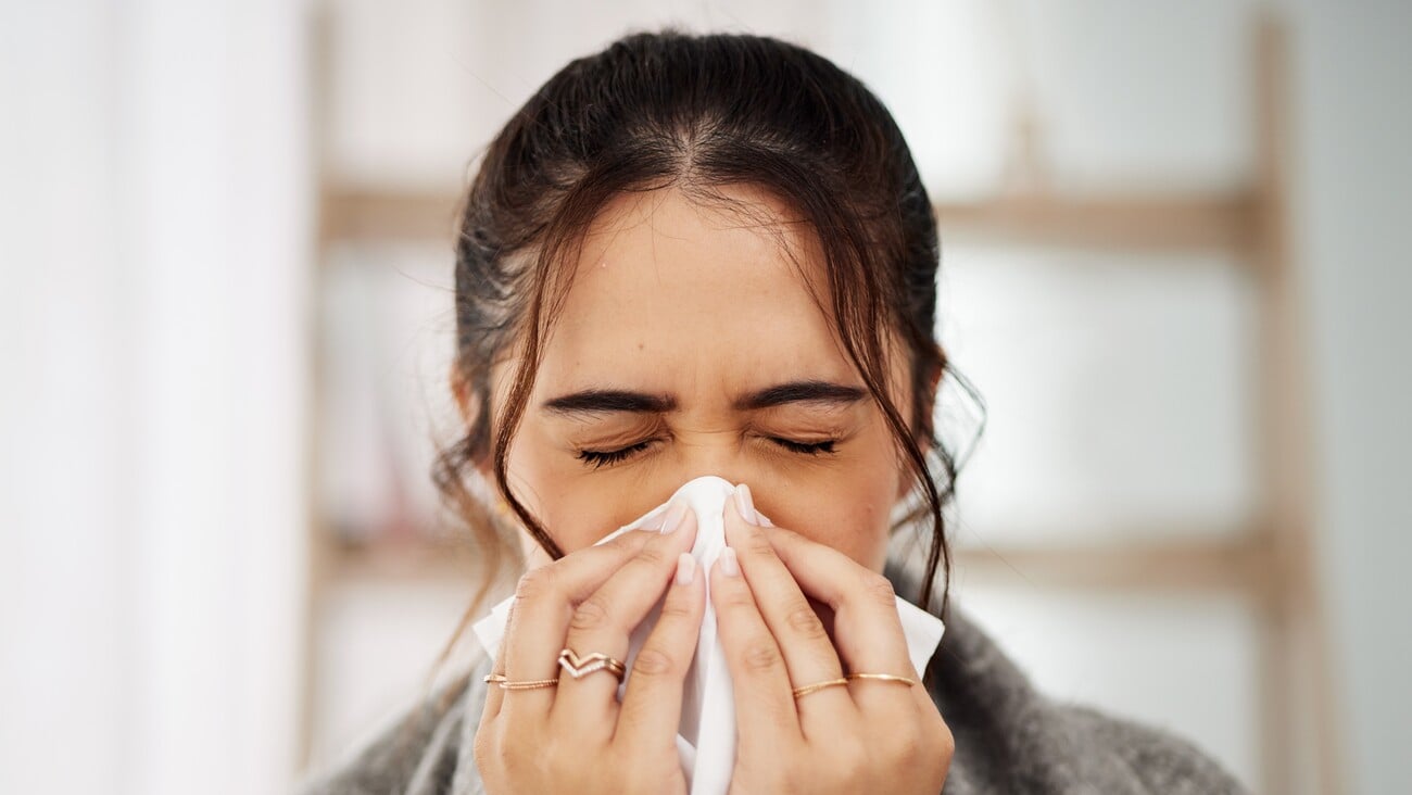 Tissue, nose and sick woman sneezing in living room with allergy, cold or flu in her home. Hay fever, sinusitis and female with viral infection, risk or health crisis in lounge with congestion; Shutterstock ID 2338427615