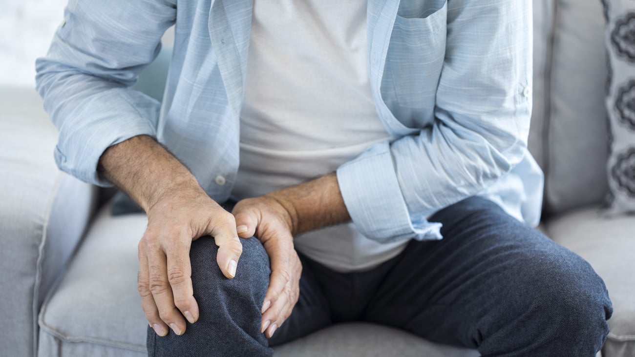 Old man suffering from knee pain sitting sofa; Shutterstock ID 682005259