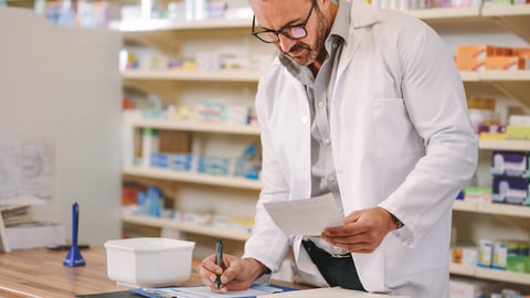 A male pharmacist checks papers in a pharmacy