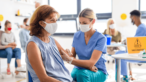 patient wearing mask and getting a shot in the arm