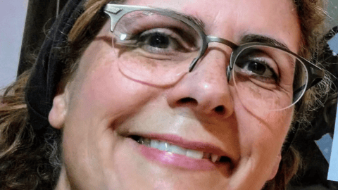 a close up of a woman wearing glasses and smiling at the camera