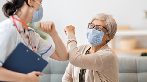 Doctor and patient both wearing masks and touching elbows