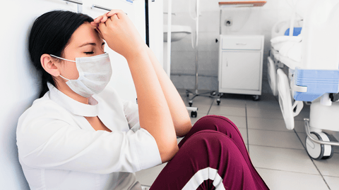 Overworked nurse sitting on hospital floor