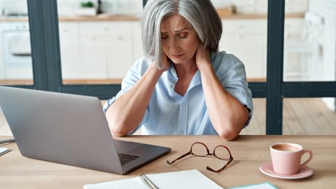 a woman sitting at a table with a laptop and smiling at the camera