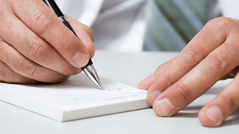 closeup of a doctor writing a prescription