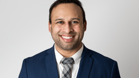 a man wearing a suit and tie smiling at the camera