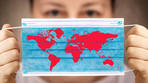 a healthcare worker holds up a surgical map that is printed with a map of the world.