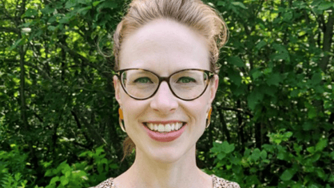 a woman wearing glasses and smiling at the camera