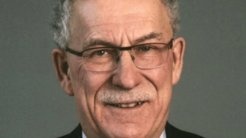 a man wearing a suit and tie smiling and looking at the camera