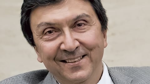 David Naylor wearing a suit and tie smiling at the camera