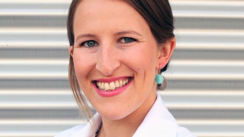 a woman wearing a white shirt and smiling at the camera