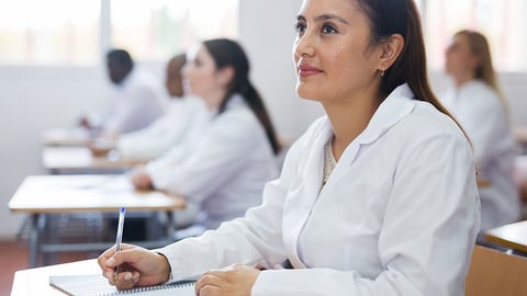 pharmacist student wearing white coat in a classroom setting