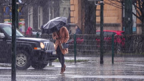 Person on street hunched over holding umbrella