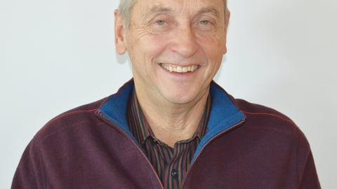 Older white man smiling in red shirt