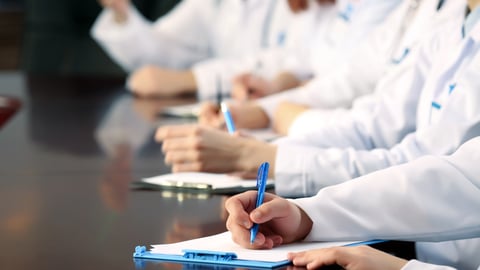 people in white coats taking notes at a meeting