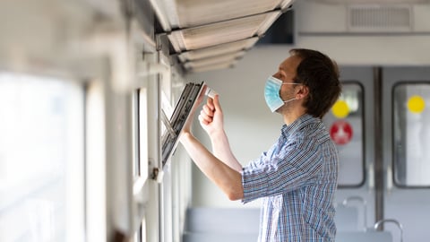 Man wearing surgical mask opening a window