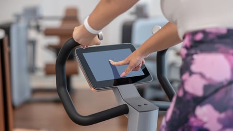 Woman pushing buttons to start her workout on an exercise bike