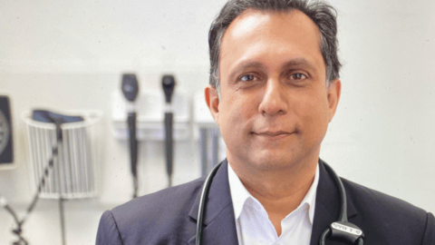 Middle aged doctor standing in front of instruments in clinic room