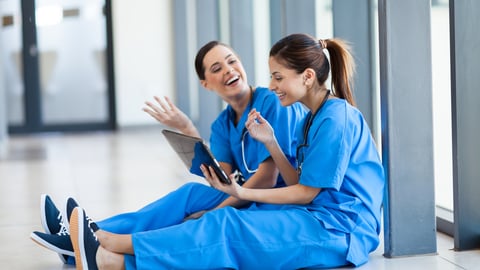 two doctors sitting together looking at a tablet