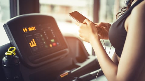 woman choosing music to listen to while exercising on the treadmill
