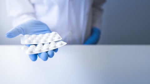 Pharmacist wearing blue glove with blister pack pills