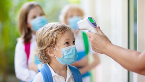 Little kids getting their temperature taken before being allowed to enter school