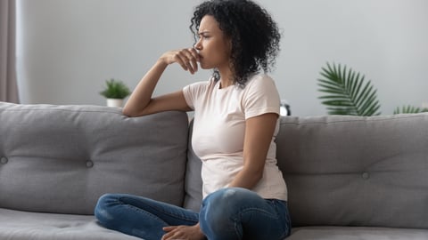 woman sitting on couch looking concerned into the distance