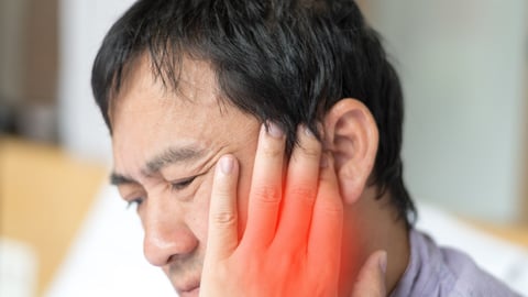 Man holding side of his face to indicate pain