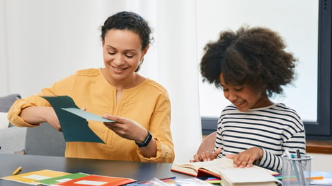 Young Black girl working on homework with her mother