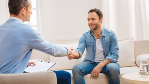 Doctor shaking patients hand while both remain sitting