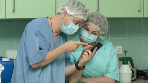 Two healthcare workers sharing a laugh over a joke on one of their phones