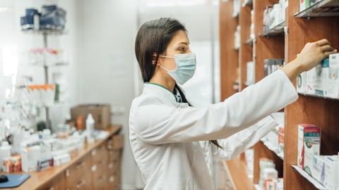 Pharmacist reaching for something on the shelf