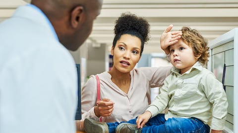 Young woman speaking with pharmacist about her child possibly having a fever